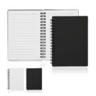 Three spiral-bound notebooks are displayed: one open with lined pages, and two closed, one with a black cover and one with a white cover. They are arranged against a plain white background.