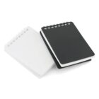 Two spiral-bound notebooks are placed side by side, one with a black cover and the other with a white cover. The notebooks are positioned diagonally on a white background, with the spirals at the top.