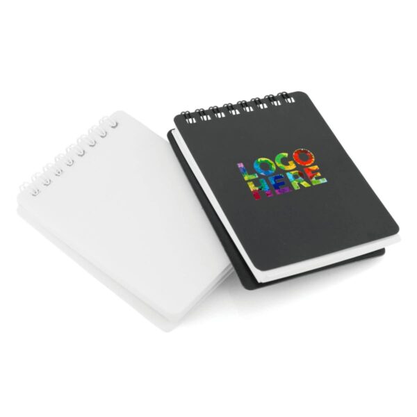 Two spiral-bound notebooks are shown, one with a white cover and the other with a black cover marked LOGO HERE in colorful lettering. They are stacked together, with the black notebook on top, slightly open, revealing lined pages.