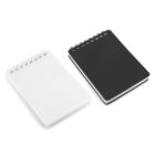 Two spiral-bound notepads are side by side on a white surface. The left notepad has a white cover, while the right one has a black cover. Both have a simple, plain design.