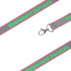 Gray lanyard with a metal clip, featuring the text Retirement Services in green, bordered by pink edges, shown against a white background.