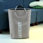 Beige laundry basket with metal handle on tiled floor near blue couch.