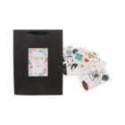 Black gift bag with floral card and assorted stickers beside it.