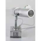 Silver spotlight with adjustable stand and wire, positioned on a small metallic base.