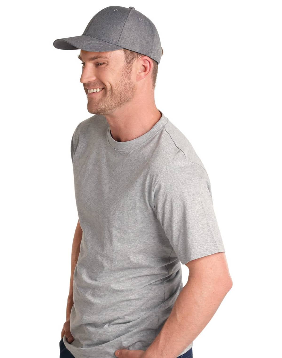 Smiling man in a gray t-shirt and cap, hands in pockets, looking to the side.