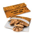 Two reusable sandwich bags, one open and one closed. The open bag is partially filled with chocolate chip cookies. Both bags are orange with black, intricate floral designs, and feature text: We print your logo here.