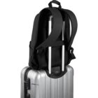 Black backpack secured on top of silver rolling suitcase with extended handle.