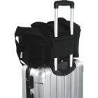 Black duffel bag placed on top of a silver rolling suitcase with an extended handle.