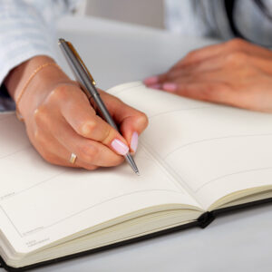 Woman writing on a black, custom-branded diary