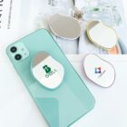 Green smartphone with two oval mirrors on top, two more mirrors nearby on a magazine.
