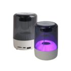 Two portable Bluetooth speakers; one lit with a purple glow.