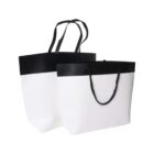 Two black and white shopping bags with handles on a white background.