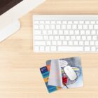 A desk with a keyboard, mouse, mouse pad, and two cards.