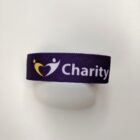 A purple wristband featuring a stylized heart design next to the word Charity in white text.