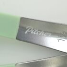Close-up of metal tool with Pitcher engraved, featuring green rubber handle.