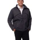 Man wearing a dark jacket and trousers, smiling with hands in pockets.
