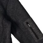 Close-up of a dark gray textured fabric jacket sleeve with a zippered pocket.