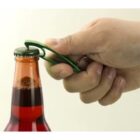 Hand using a green bottle opener to open a glass bottle with a metal cap.