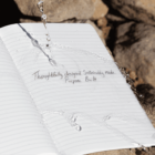 Water splashes on an open notebook with handwritten text, surrounded by rocks.