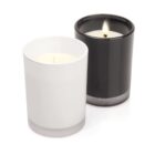 Two glass candles: one white and unlit, one black and lit with a visible flame.