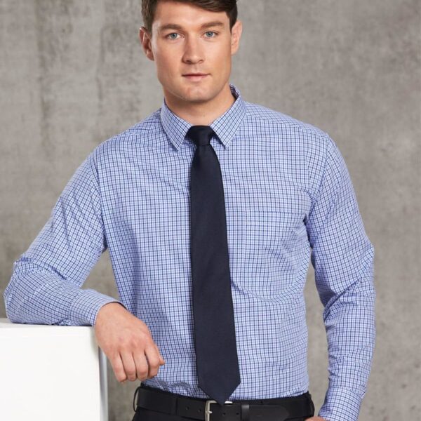 Man in a blue checked shirt and black tie standing against a gray background.