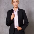 Person in a black suit with a pink shirt, standing against a gray background.