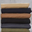 Stack of folded pants in beige, navy, brown, black, dark gray, and olive green.