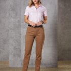 Person in a pink shirt and brown pants stands against a gray background.