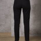 Person wearing black trousers standing against a concrete wall.