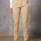 Person in beige pants, white shirt, and black shoes; standing against a gray wall.