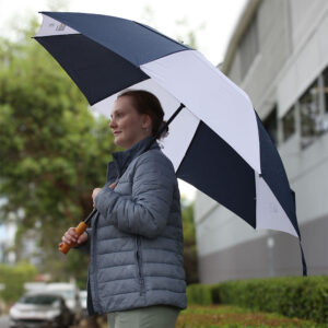 Person holding a large umbrella from articles while standing outside on a rainy day.