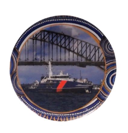Decorative plate with a ship and bridge design, featuring blue and gold patterns.