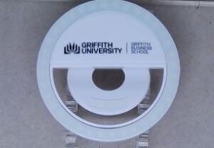 Round Griffith University Business School phone clip light on a surface.