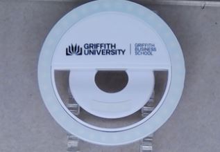 Round Griffith University Business School phone clip light on a surface.