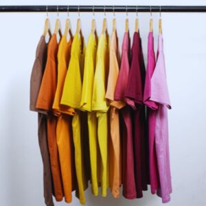 A row of colorful, custom branded promotional tee shirts, arranged from brown to pink.