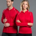 Two people in matching red long-sleeve shirts standing against a gray background.