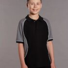 Smiling boy in a black shirt with gray sleeves, standing against a plain background.
