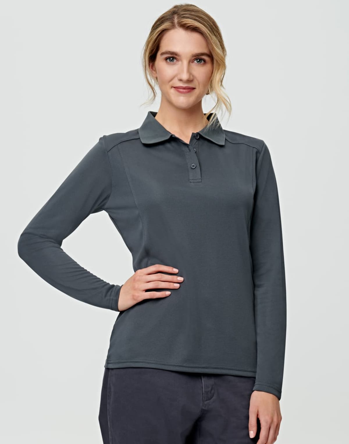 Person in a dark long-sleeve shirt with one hand on hip, smiling at the camera.