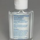 Clear plastic bottle of hand sanitiser with blue text detailing ingredients and usage instructions.