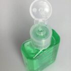 Open bottle of green liquid hand sanitizer with a flip-top cap on a plain background.
