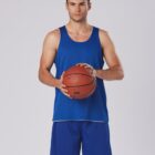 Man in blue basketball attire holding a basketball against a plain background.