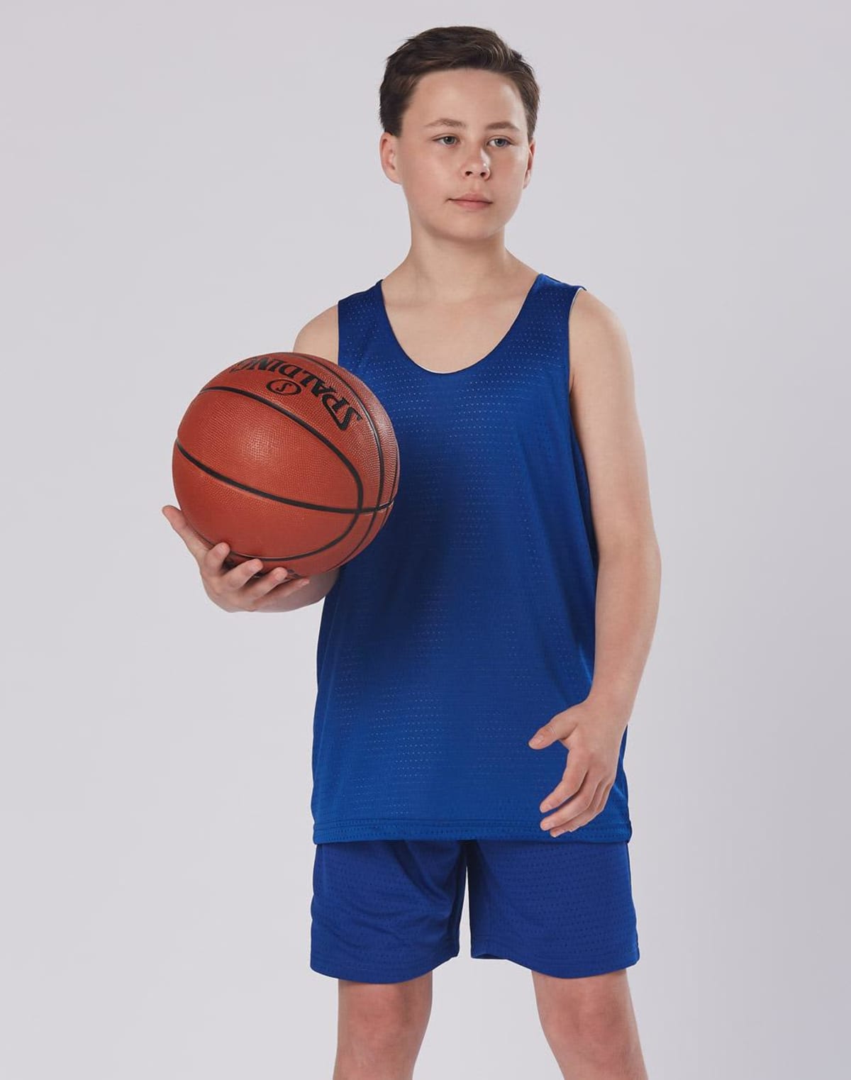 A young person in a blue basketball outfit holding a basketball.