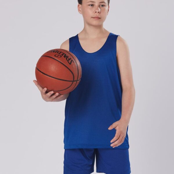 Boy in blue basketball attire holding a ball, standing against a plain background.