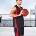 Person in black and red basketball attire holding a ball on an outdoor court.