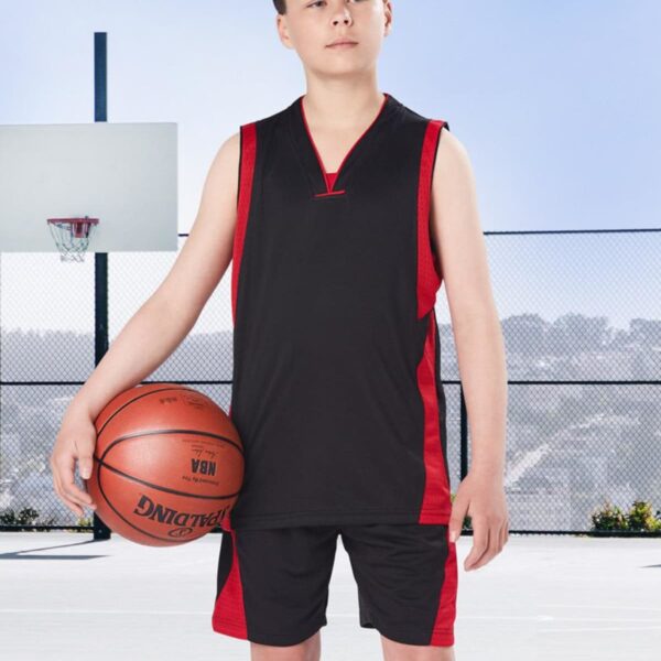 Youth in basketball attire holding a ball on an outdoor court.