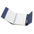 A blue spiral-bound notebook is open, with lined pages visible. It has a blue cover and an attached pen in the holder on the right side. The notebook is spread flat on a white background.