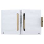 Open spiral notebook with lined pages. A pen is placed in the holder on the right. A small recycling symbol is printed at the bottom corners of each page. Cover is partially visible, suggesting eco-friendly materials.