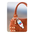 A Chevron key tag hangs from the handle of a brown handbag with gold studs.
