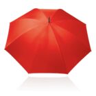 A bright red umbrella is fully open and viewed from above, showcasing its vibrant color and radial pattern. It casts a subtle reflection on the shiny white surface beneath it.