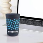 Branded cup in front of a laptop on a desk with abstract decor.